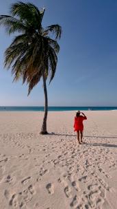 行走在沙滩上的红衣女人