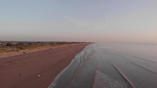 上升无人机拍摄日落时的海滩，潮湿的红沙和日落红波