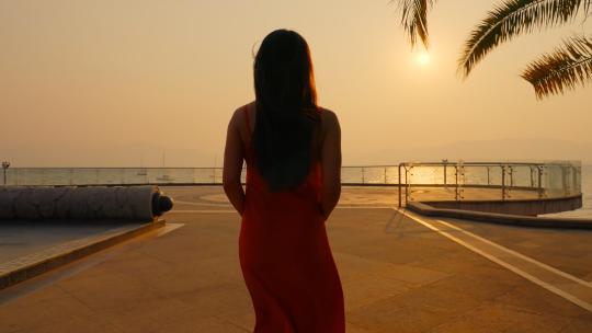 夕阳下晚霞里穿着红色裙子的美女背影剪影视频素材模板下载
