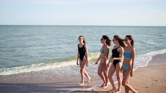女孩穿着泳衣在热带沙滩上海边散步