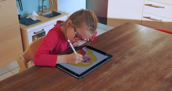 小女孩在家用平板电脑画画