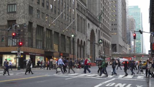 多云雨天期间，人们在建筑物之间的街道上忙碌的人群NYC NY USA曼哈顿，纽约市，美利坚合众国美国人