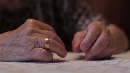 一个老寡妇摘下订婚戒指。孤独和悲伤的概念。特写