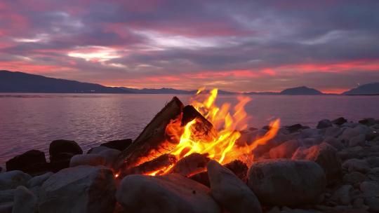 夕阳西下海边旁的篝火燃烧木材燃烧户外露营