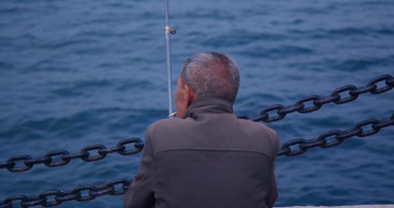 休闲生活老人海边钓鱼特写背影烟台大海风光