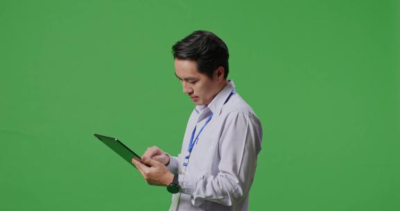 亚洲商人在工作室的绿屏背景上使用平板电脑的侧视图