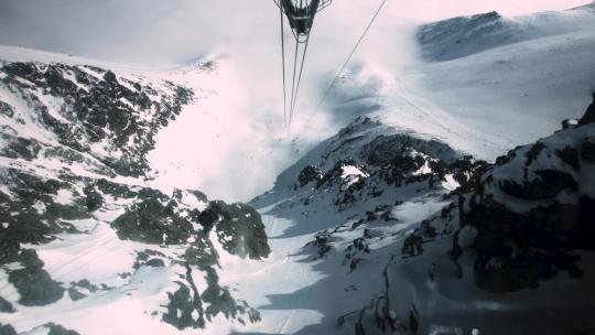 滑雪的POV在锯齿状山峰之间的电缆上沿着积雪的小径升起