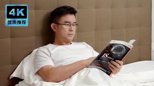 男子在床上看杂志居家看书疲惫揉眼睛困倦视频素材模板下载