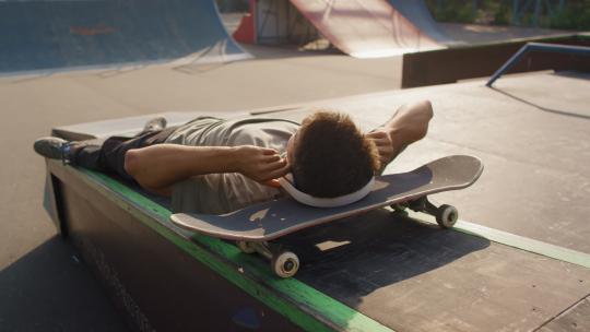 青少年枕着滑板听音乐