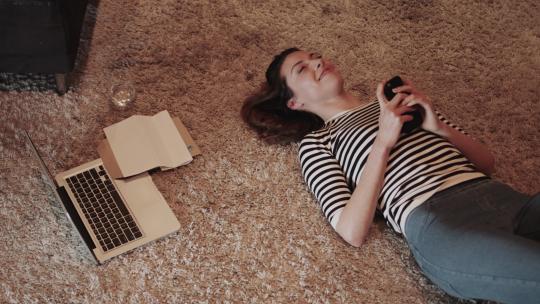 女人工作完躺在地毯打电话