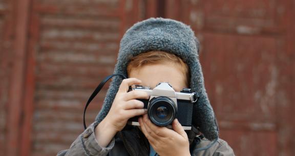 小男孩在户外拿着相机拍摄