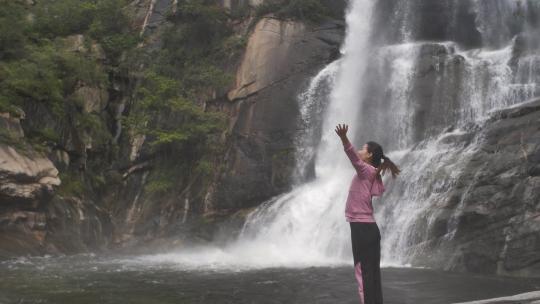 中国人女性在瀑布下张开双臂拥抱自然