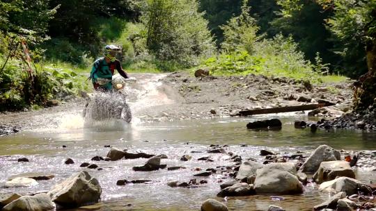 越野摩托车手在山上过一条河