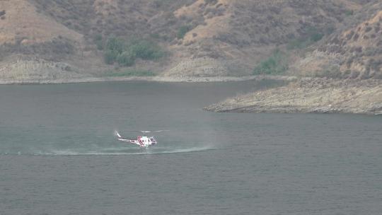 直升机在大火烧毁的山坡后装水