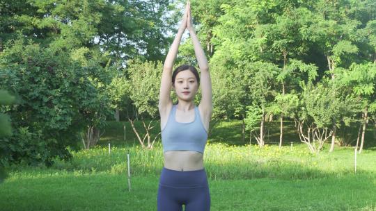 户外草地上做瑜伽的年轻女性身穿运动服装视频素材模板下载