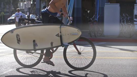 带冲浪板骑自行车的男人视频素材模板下载