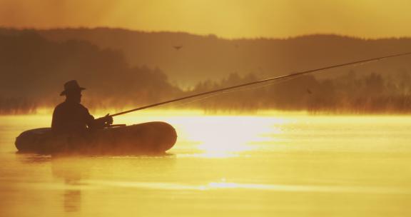 夕阳下乘坐皮划艇的钓鱼人