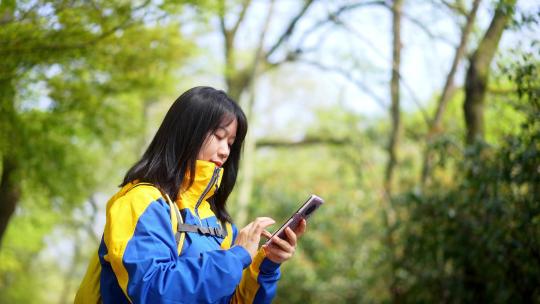 年轻阳光活力女孩春天户外踏青游玩刷手机