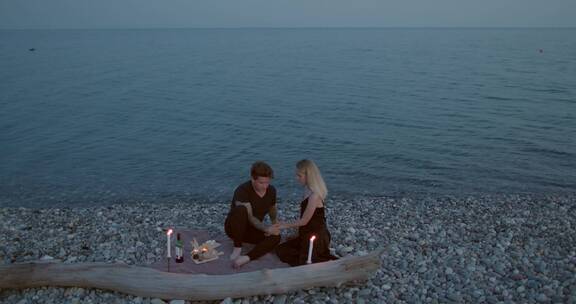 一对情侣在岩石海岸互相亲吻和晚餐约会
