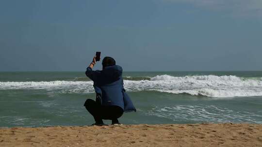 海边人物拿手机拍摄
