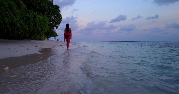 美女走在黄昏下的海滩上
