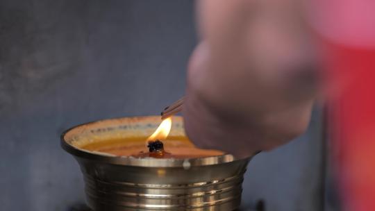 在寺庙里一个信徒在用油灯点燃香火