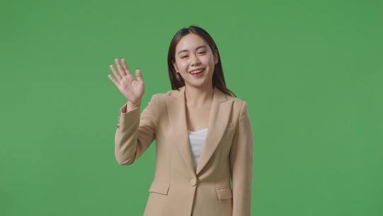 亚洲女商人挥手微笑而站在绿色屏幕在的工作室视频素材模板下载