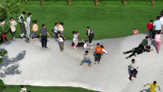 航拍六一儿童节小朋友在游乐园玩耍滑梯木马