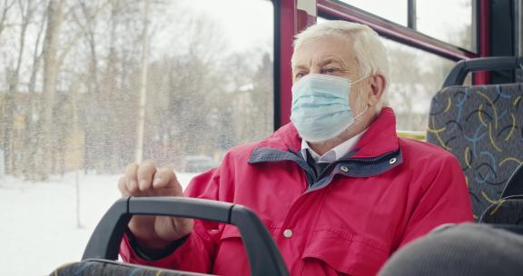 戴医用口罩的老人坐在公共汽车上