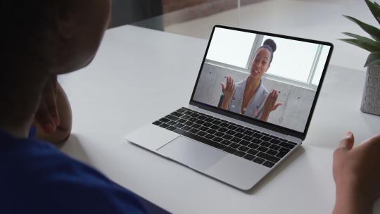 非裔美国妇女在家与女办公室同事在笔记本电脑上进行视频通话