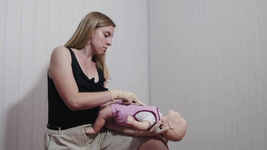 一位妇女演示如何在婴儿身上应用心肺复苏