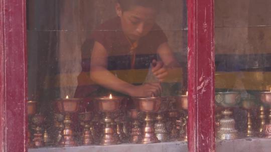 西藏小和尚窗外视角摆弄杯子蜡烛