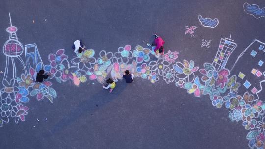 一群孩子在地上用粉笔作画