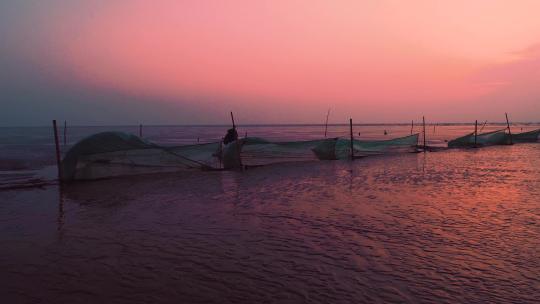 航拍黄海岸边渔民在朝霞下捕鱼