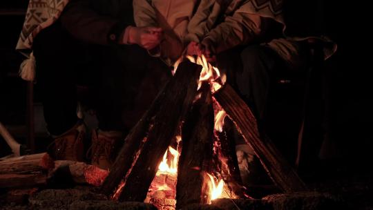 一家人户外露营坐在篝火旁取暖