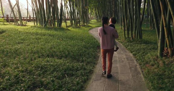妈妈抱着小女儿散步阳光竹林公园