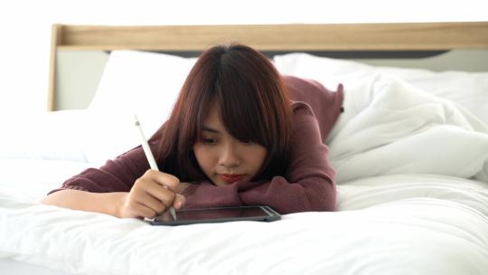 女孩趴在床上玩手机视频素材模板下载