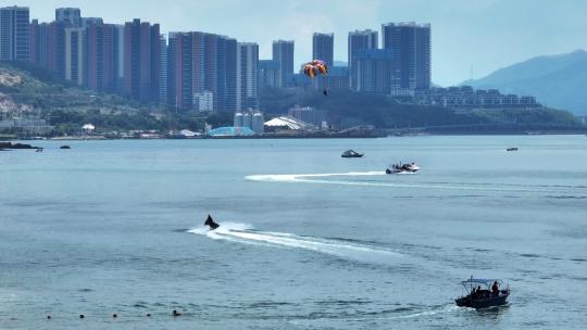 航拍海滨城市游艇飞行的滑翔伞极限运动