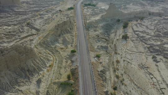 空旷公路的鸟瞰图，穿过崎岖干旱的俾路支沙漠景观。倾斜的基座视频素材模板下载