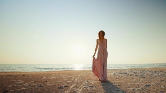 穿着长裙的女人走在沙滩