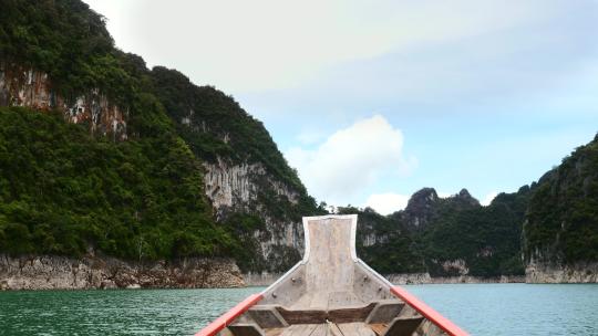 在靠近石灰岩悬崖和热带森林的木长尾船上游览湖上视频素材模板下载