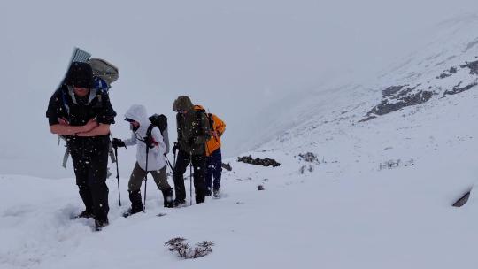 攀登岷山山脉都日峰的登山者在雪中徒步行进