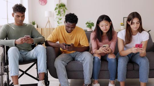 青年们在家里一起玩手机