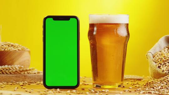 玻璃杯中的啤酒和手机对比的特写