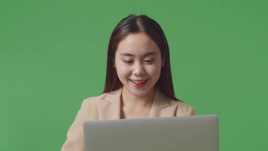 亚洲女商人使用笔记本电脑并在绿屏工作室对着镜头微笑的特写镜头