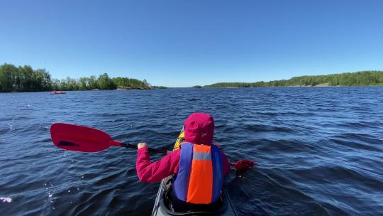 人划运动皮划艇沿着湖水在蓝天