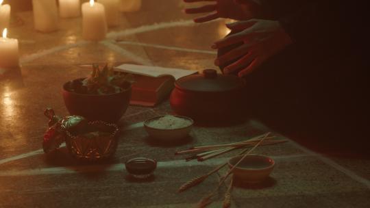 女巫坐在五角星圆圈里煮药水。邪恶的女巫在晚上举行仪式和牺牲，使用黑色巫术，地板上的蜡烛。万圣节传统，美国节日。