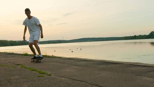 一个年轻人在湖边玩滑板