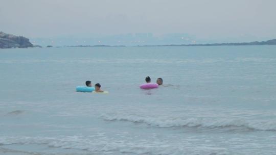小孩戴游泳圈在海里游泳