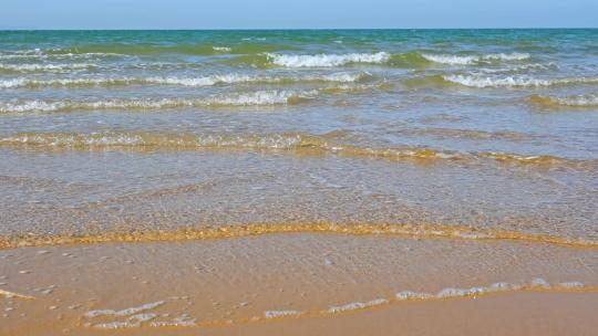 夏天的海边海滩上波浪泛起朵朵浪花